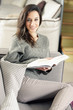 Portrait of a happy young woman lying on couch with book