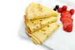 Crepe on a plate with a strawberry, a raspberry and a bilberry
