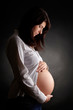 Photo: Pregnant woman over dark background Pregnant woman over dark background