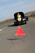 Warning triangle set on the road by broken down car Warning triangle set on the road by broken down car