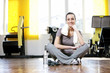 young woman sitting on the gym's floor after workout