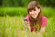 Photo: Young woman with mobile phone lies on green grass Young woman with mobile phone lies on green grass