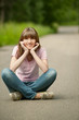 Photo: Young beautiful woman sits in lotus pose on road Young beautiful woman sits in lotus pose on road