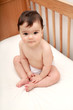 Foto: Cute baby sat in cot looking to camera Cute baby sat in cot looking to camera