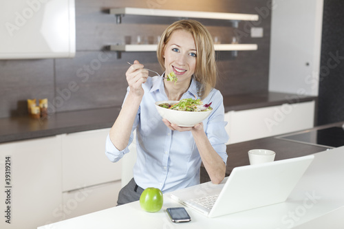 Photo: junge frau isst salat in der küche junge frau isst salat in der küche