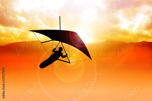 Photo: Silhouette of a man figure gliding during sunrise Silhouette of a man figure gliding during sunrise