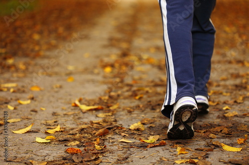 Photo: Woman walking cross country trail in autumn forest Woman walking cross country trail in autumn forest