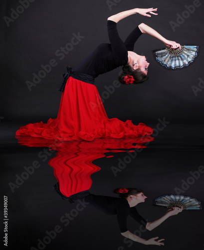 Foto: Attractive spanish young woman dancing flamenco over black backg Attractive spanish young woman dancing flamenco over black backg