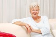 Friendly elderly lady sitting on sofa