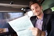 Foto: Happy man reading news in luxury car Happy man reading news in luxury car