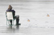 Young fisherman catching a fish on a frozen lake in winter.