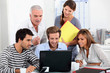 Young people and their manager sitting round a laptop computer