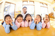 頬杖をついて微笑む幼稚園児と笑顔の幼稚園教諭