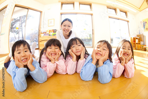 Photo: 頬杖をついて微笑む幼稚園児と笑顔の幼稚園教諭 頬杖をついて微笑む幼稚園児と笑顔の幼稚園教諭