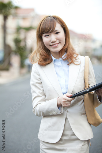 Foto: タブレットPCを持って歩く笑顔のOL タブレットPCを持って歩く笑顔のOL