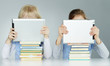 Foto: Two pupils leaning on a pile of books while reading on touchpad Two pupils leaning on a pile of books while reading on touchpad