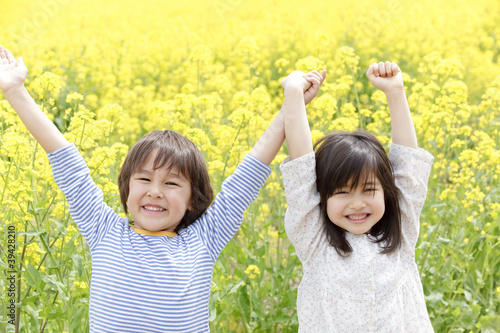 Photo: 菜の花畑で両手を挙げる男の子と女の子 菜の花畑で両手を挙げる男の子と女の子