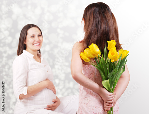Foto: Little daughter has a flowers for her pregnant mother Little daughter has a flowers for her pregnant mother