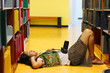 The girl lay down on the floor of the library with the camera