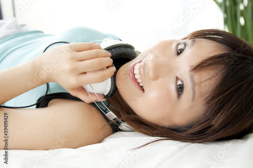 Photo: ベッドで寝転んで微笑む女性 ベッドで寝転んで微笑む女性