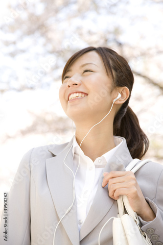 Photo: 音楽を聴きながら桜を見上げる通勤中の女性 音楽を聴きながら桜を見上げる通勤中の女性
