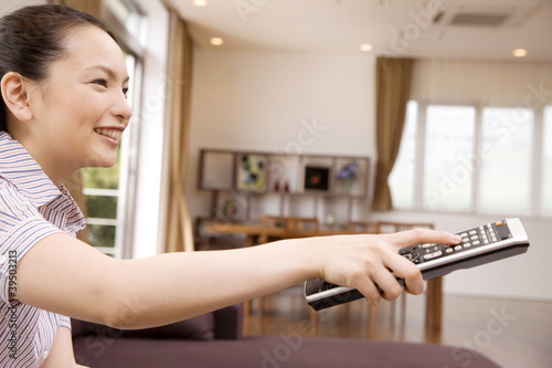 Photo: テレビのチャンネルを変えようとする女性 テレビのチャンネルを変えようとする女性