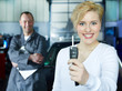 Satisfied customer shows car key, mechanic at the background