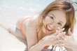 波打ち際で寝そべる水着女性