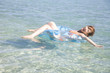浮き輪に乗って海を泳ぐ水着女性