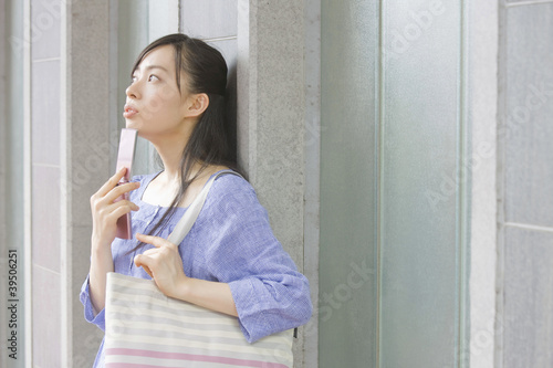 Photo: 携帯電話を持って上を眺める女性 携帯電話を持って上を眺める女性