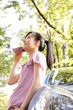 車に寄りかかって電話をする女性
