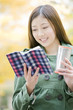 公園で飲み物を持ちながら読書する女性