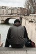 homme assis au bord de la seine à Paris
