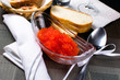 Red caviar in a glass plate next to the bread