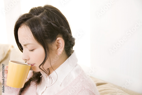 Photo: ソファに座りながらホットコーヒーを飲む女性 ソファに座りながらホットコーヒーを飲む女性
