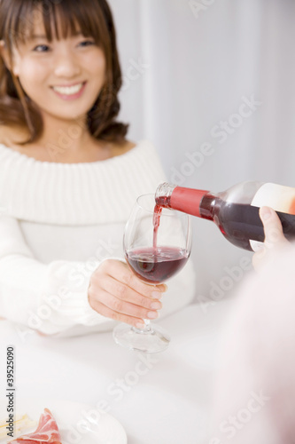Photo: ワインを友達に注いでもらっている女性 ワインを友達に注いでもらっている女性