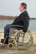 Mann sitzt im Rollstuhl in der Natur