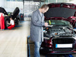 Master mechanic checking the engine bay, workers in background
