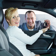Female customer in a car gets car key from master mechanic