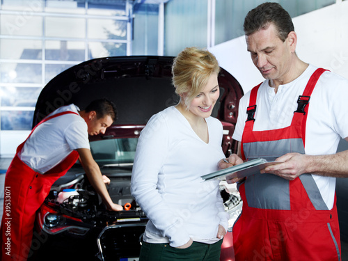 Foto: Customer and mechanic in a garage looking at a quotation Customer and mechanic in a garage looking at a quotation