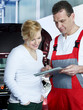 Motor mechanic explaining repair costs to female customer