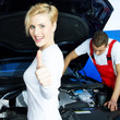 Mechanic working on engine bay, customer in front shows thumb up