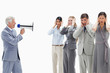 Photo: Man yelling in a megaphone at business people with their hands over their ears Man yelling in a megaphone at business people with their hands over their ears