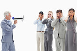 Photo: Man yelling in a megaphone at business people with their hands over their ears Man yelling in a megaphone at business people with their hands over their ears