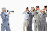 Photo: Man yelling in a megaphone at business people with their hands over their ears Man yelling in a megaphone at business people with their hands over their ears