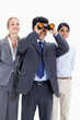 Businessman looking up through binoculars with two smiling girls behind him