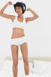 Frizzy haired young woman dancing on her bed