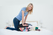 Photo: Angry looking woman trying to close her suitcase by pushing on it while on the bed Angry looking woman trying to close her suitcase by pushing on it while on the bed