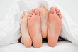 Two pairs of feet crossed over each other in bed