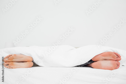 Photo: Man and woman's feet in bed turned away from each other Man and woman's feet in bed turned away from each other